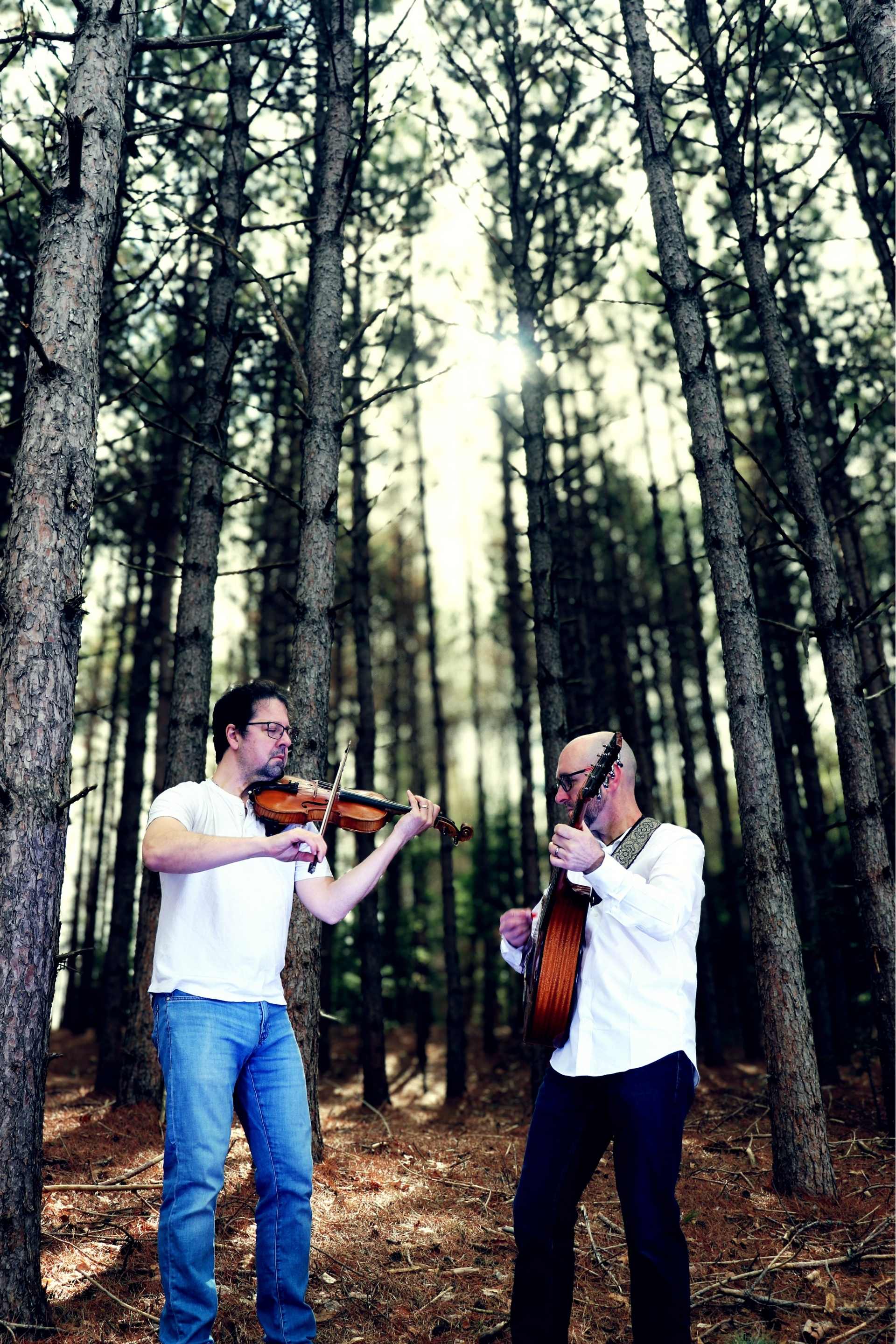 Jeremy and Andy playing fiddle and guitar in the pines